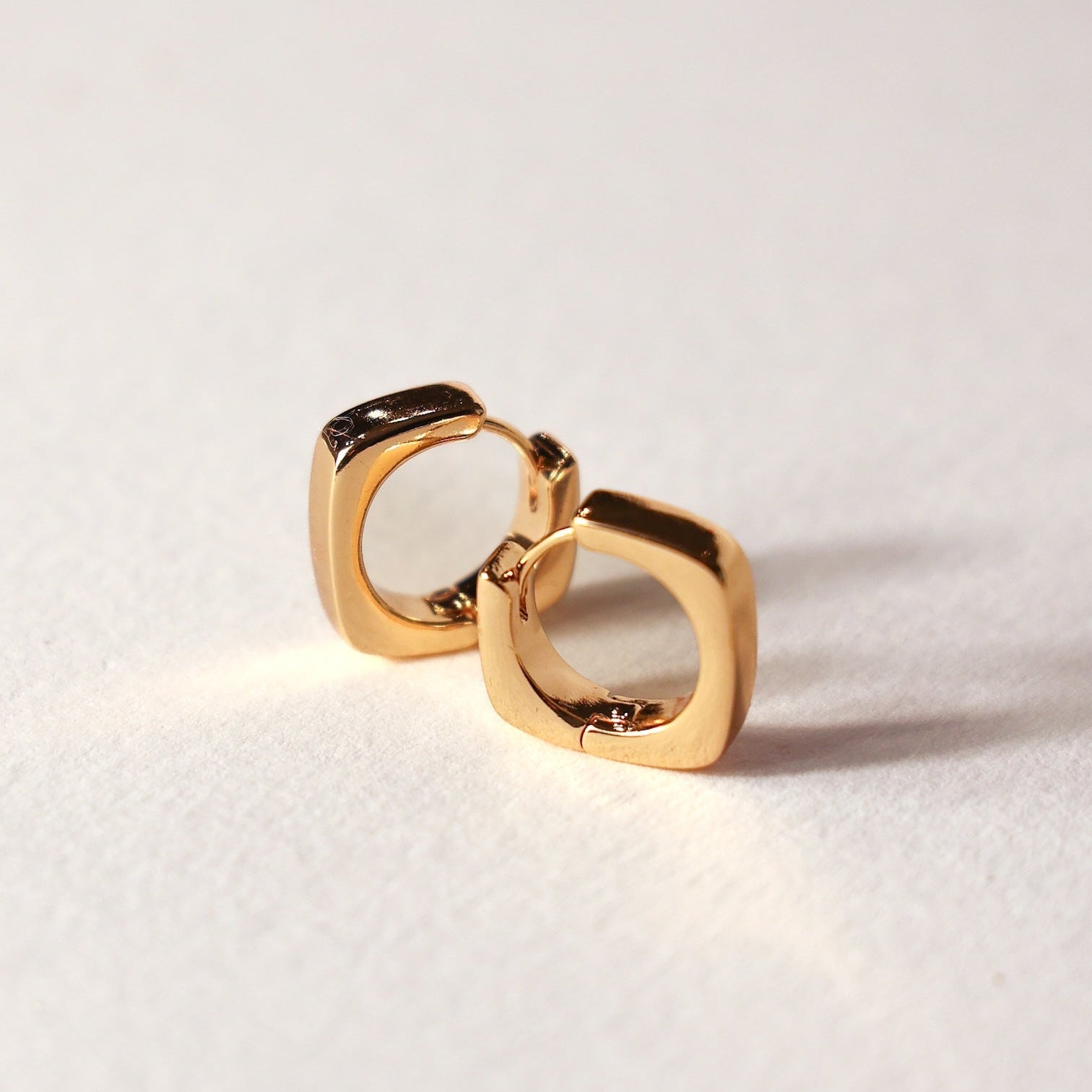 Gold square Emily hoop earrings on a light background