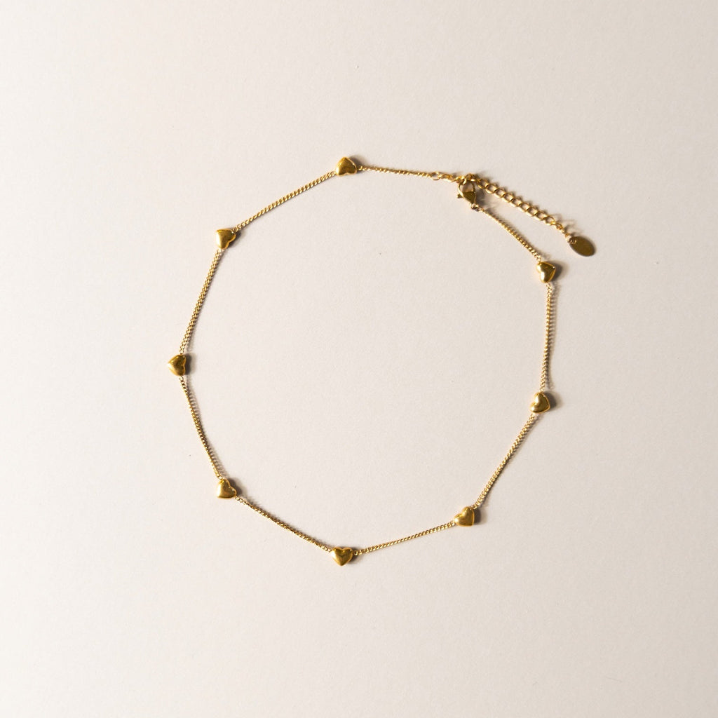 Gold heart bracelet on a light beige background