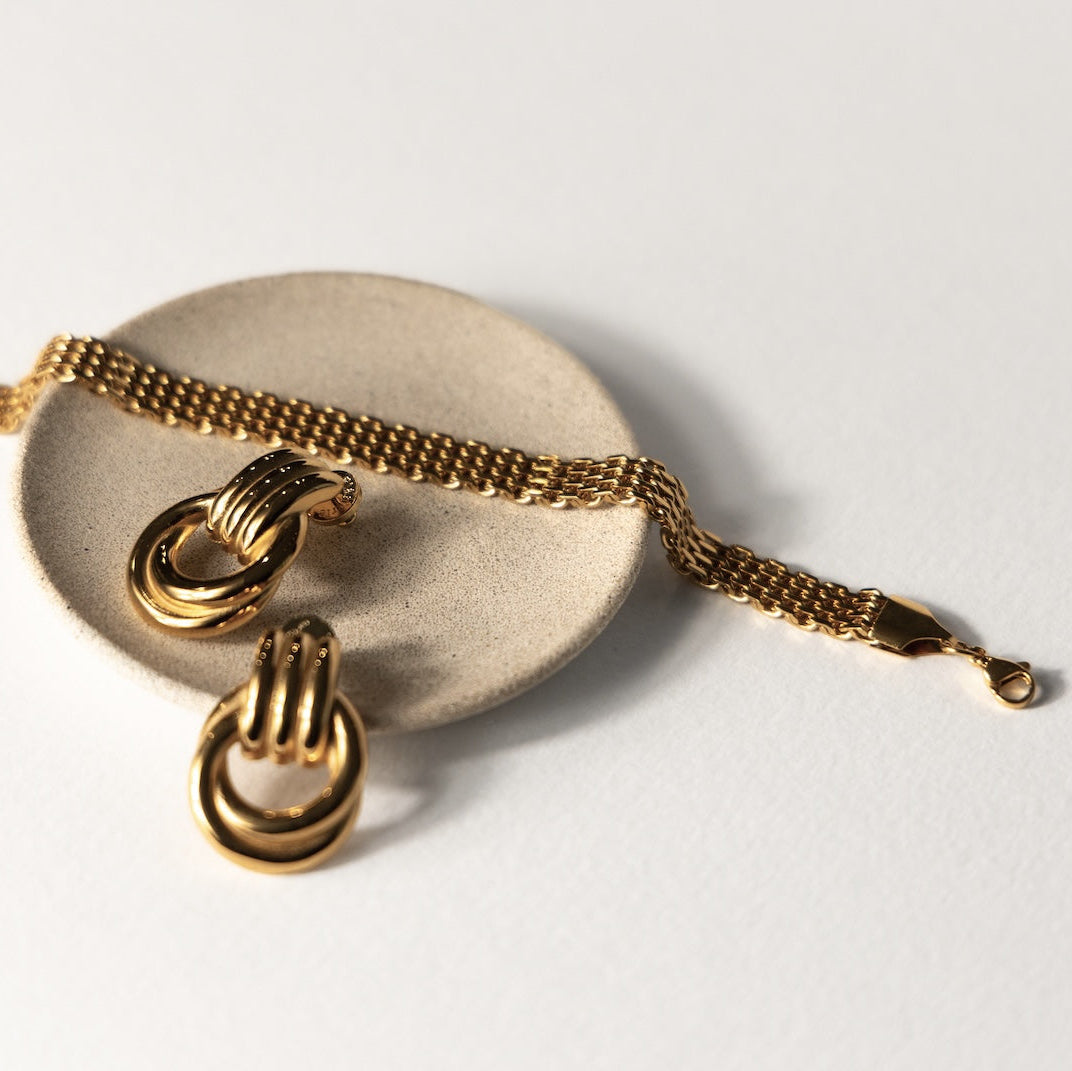 Gold bracelet with interlocking heart charms on a white background