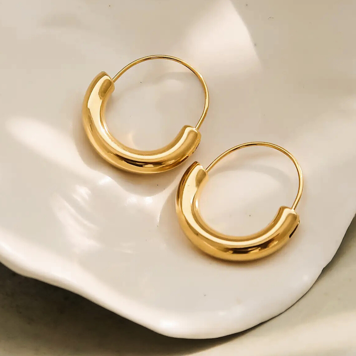 Gold hoop earrings on a white ceramic dish