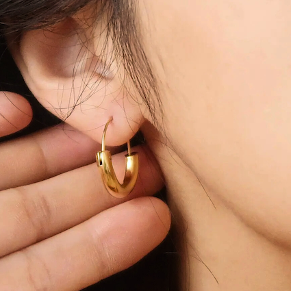 Gold hoop earring worn by a woman with black hair