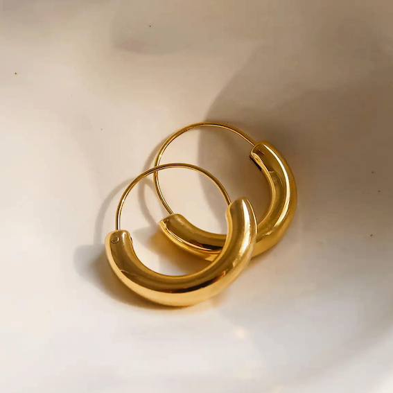 Gold hoop earrings on a white ceramic plate