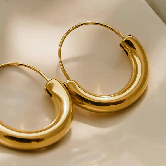 Gold hoop earrings on a light beige background