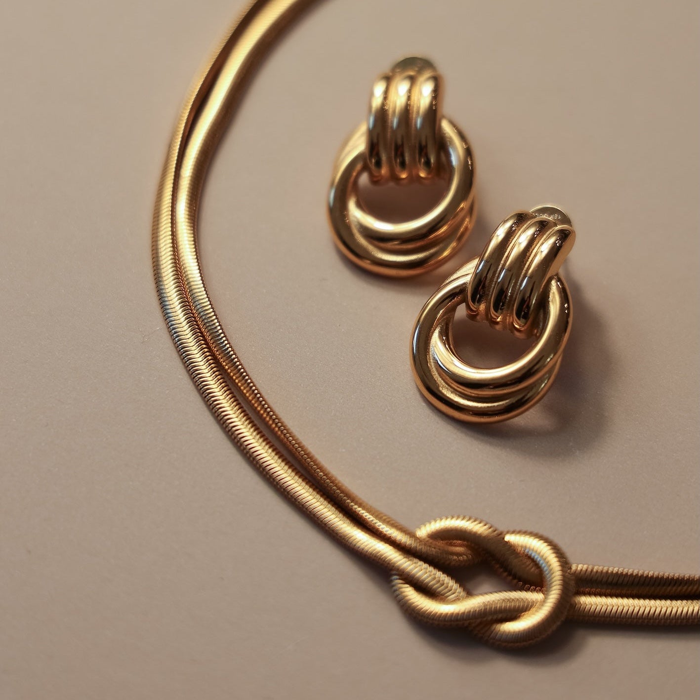 Gold hoop earrings on a beige background