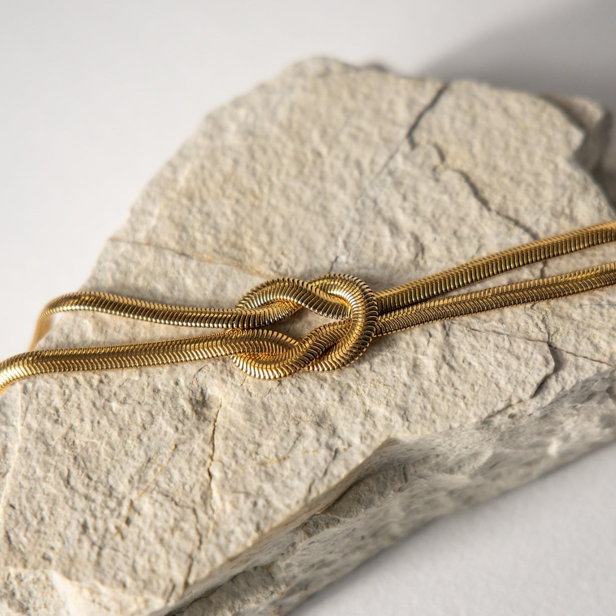 Gold knotted bracelet on a stone surface