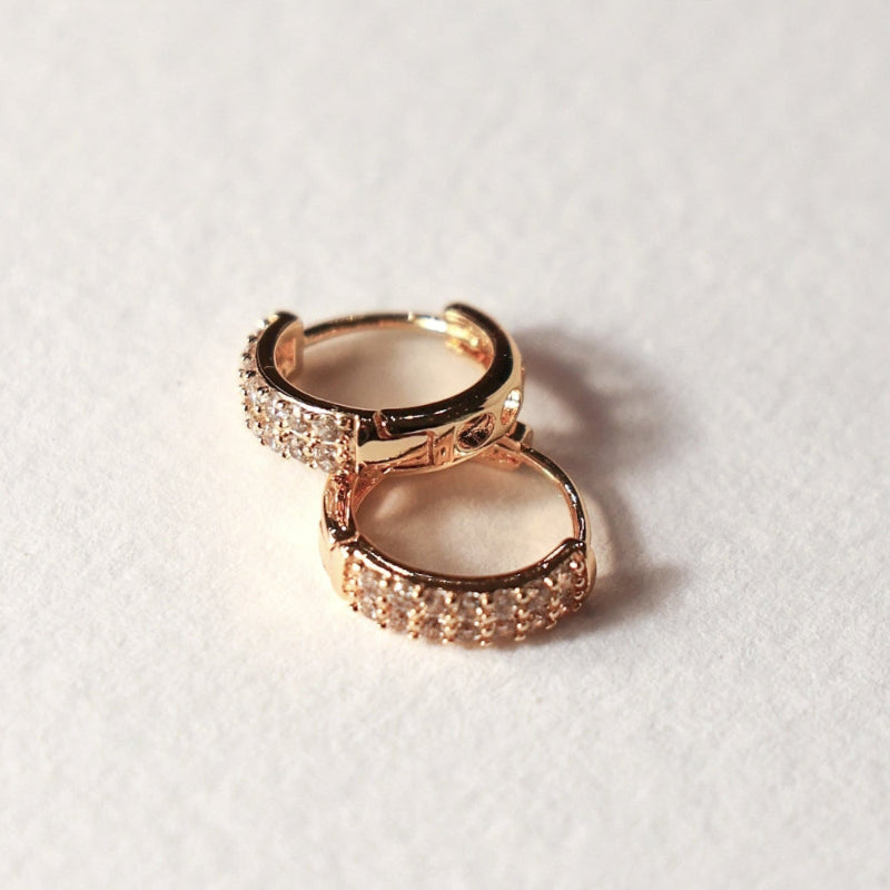 Gold minimalist hoop earrings on a light gray background