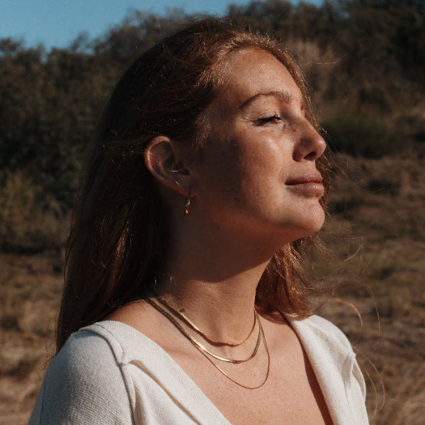 Woman with long hair and a white top standing in a natural setting