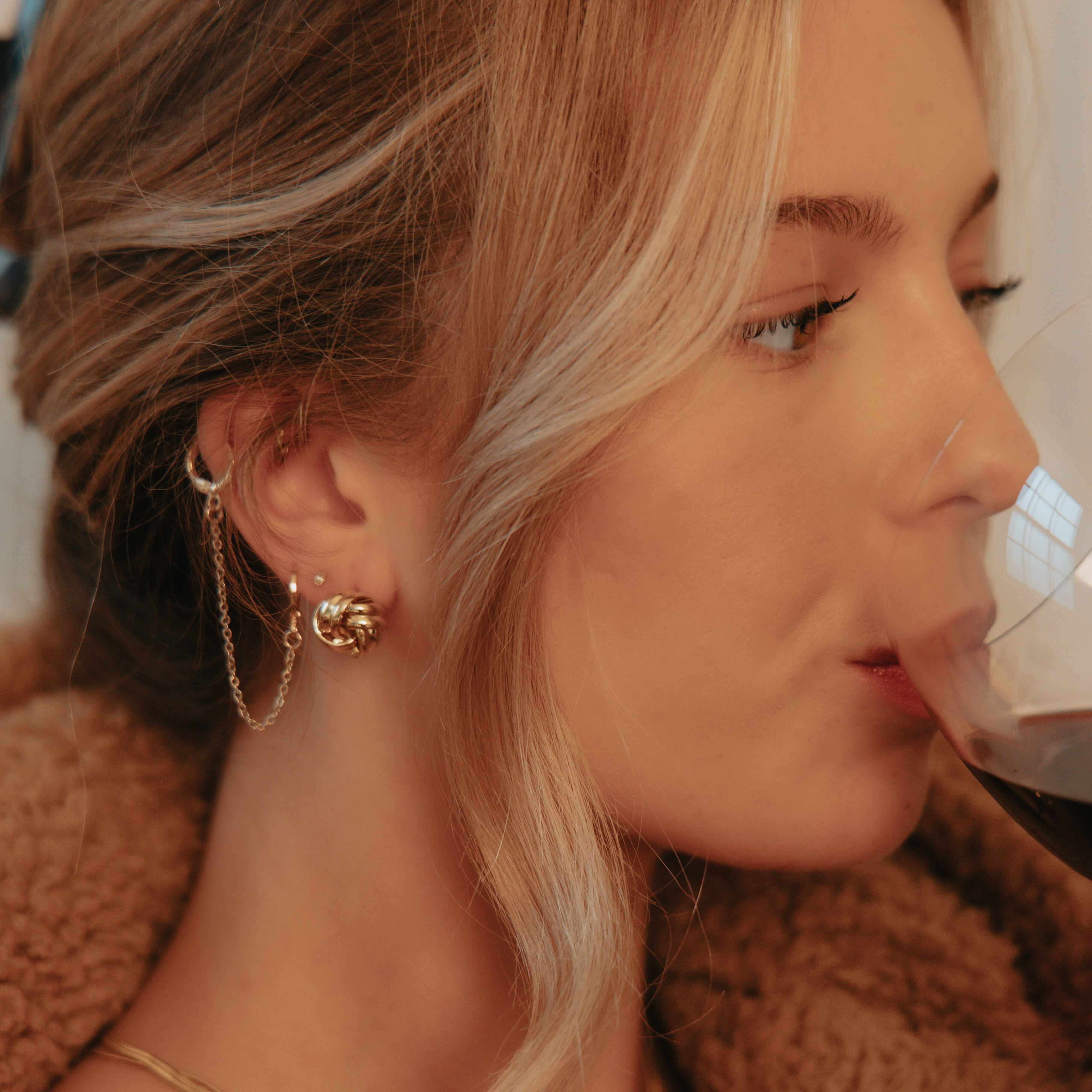 Close-up of a woman wearing gold earrings with a blurred background