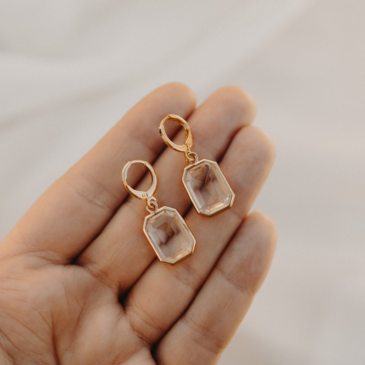 Allana faceted drop earrings held in a hand, showing their size