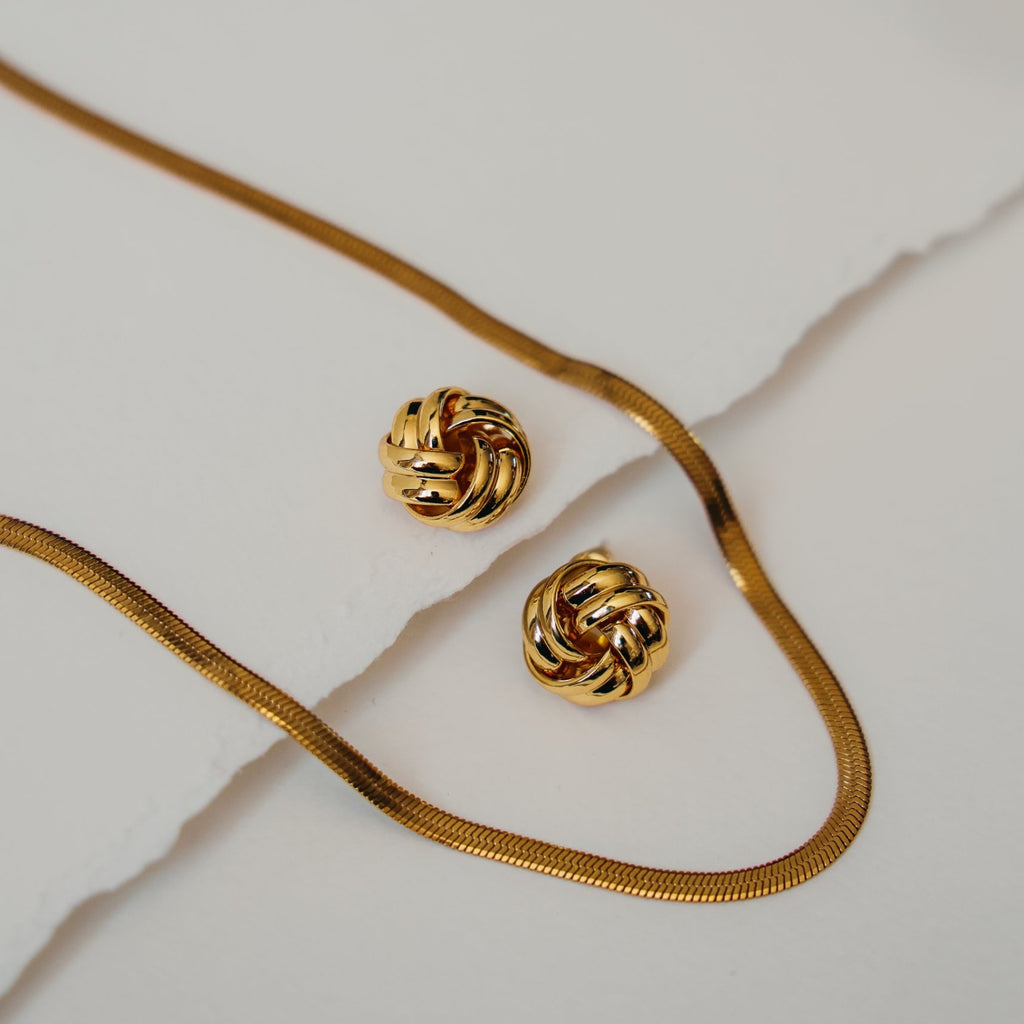 Beatrice knot stud earrings next to a gold herringbone chain