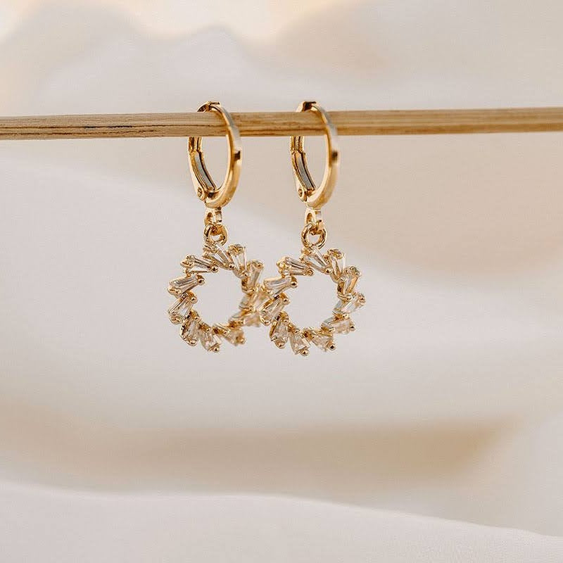 Lucy sparkle wreath earrings hanging from a wooden rail