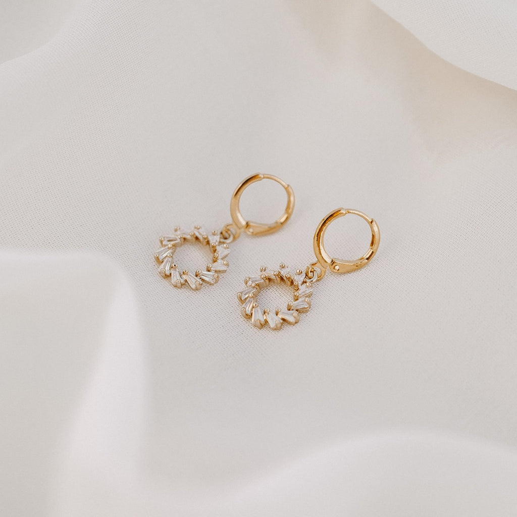 Lucy gold huggie earrings with a small circle of clear stones, on white silk