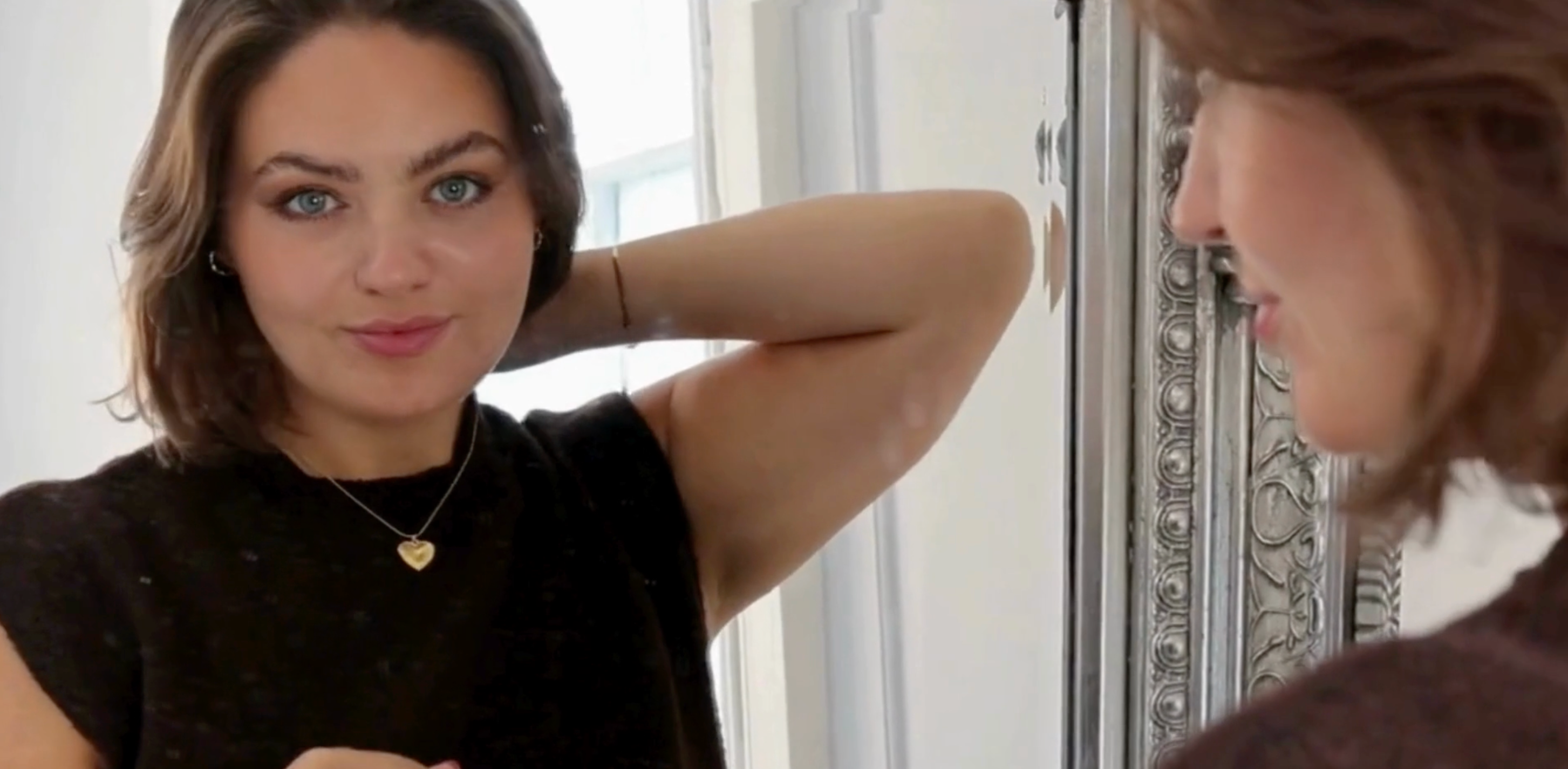 Woman adjusting gold jewellery in front of mirror