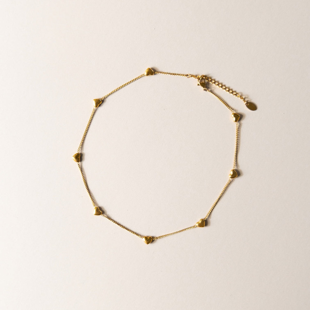 Rosie gold heart bracelet on a light beige background